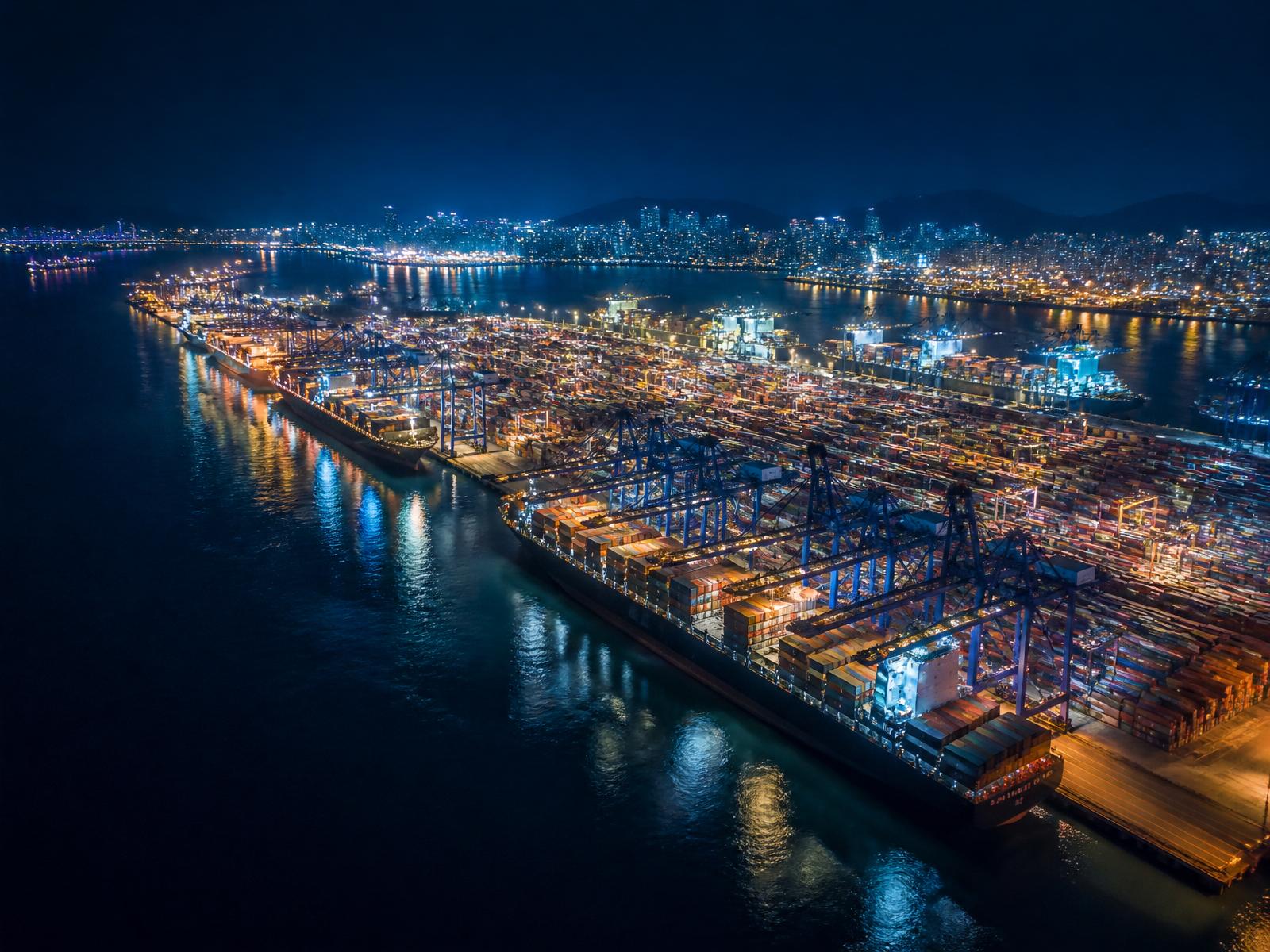International sea port hub illuminated at night with container ships and cranes